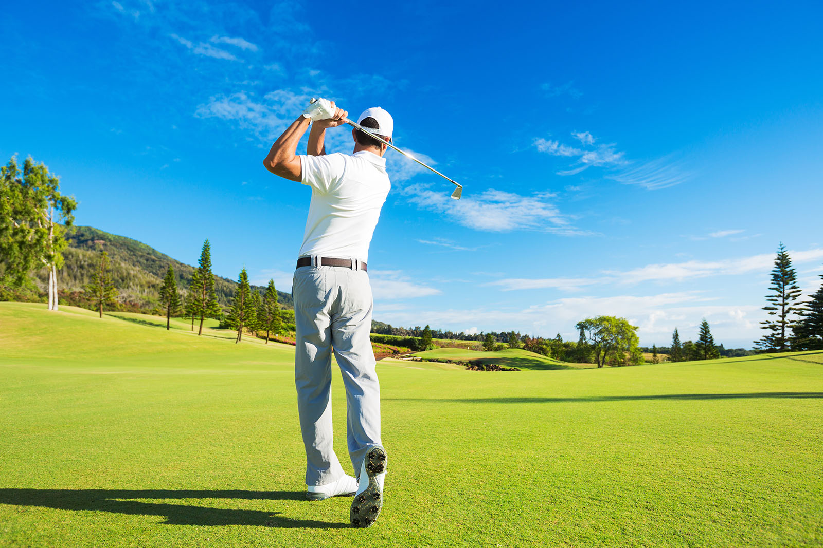Golfer mid-swing on a beautiful golf course